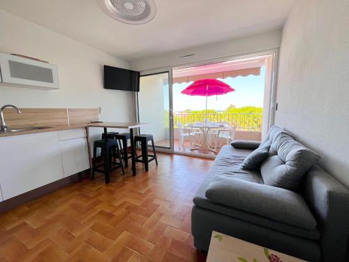 un salon avec un canapé et une table avec un parasol rouge dans l'établissement Appartement T2 avec Terrasse et Parking - 200m Plage - FR-1-309-478, à Saint-Cyprien