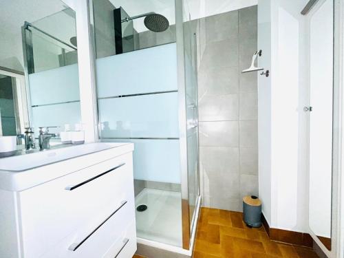 une salle de bain blanche avec une douche et un lavabo dans l'établissement Appartement T2 avec Terrasse et Parking - 200m Plage - FR-1-309-478, à Saint-Cyprien