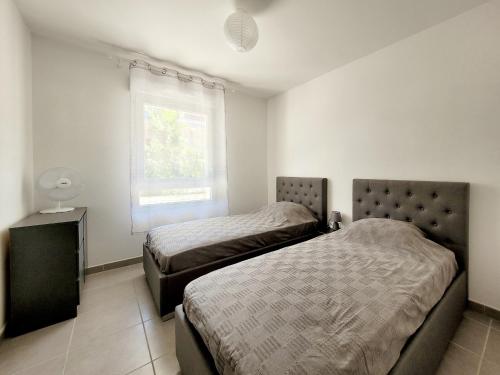 une chambre avec deux lits et une fenêtre dans l'établissement Canet-en-Roussillon: T3 moderne, RDC, 4 pers, piscine, garage, proche mer - FR-1-794-156, à Canet