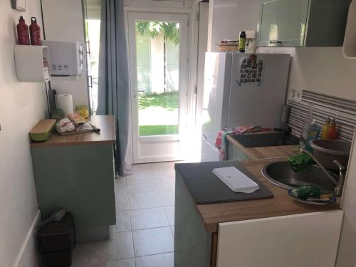 une petite cuisine avec un évier et un réfrigérateur dans l'établissement Maison Bungalow Climatisée avec Jardin Arboré, 3 Chambres, Wifi - Proche Plage et Commerces - FR-1-701-84, à Valras-Plage