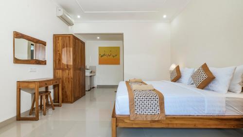 a bedroom with a bed and a desk in it at Marwati Guest House in Ubud