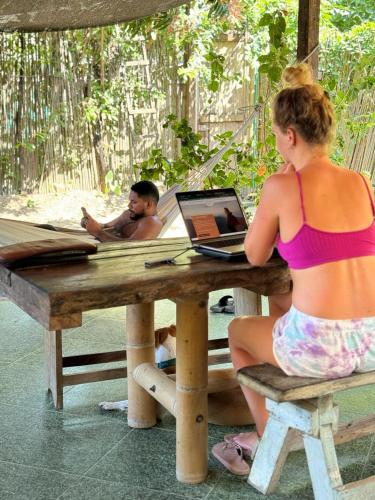 a woman sitting at a picnic table with a laptop at KUA Cabañas in Palomino