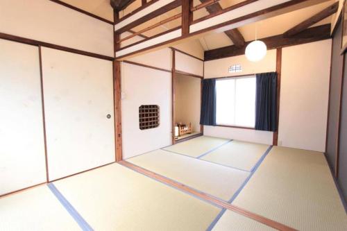 an empty room with white flooring and a window at Sunrise House 桃谷 in Osaka