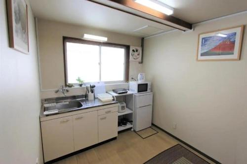 a small kitchen with a sink and a window at Sunrise House 桃谷 in Osaka
