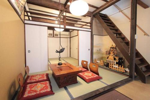 a room with a table and chairs and a staircase at Sunrise House 桃谷 in Osaka