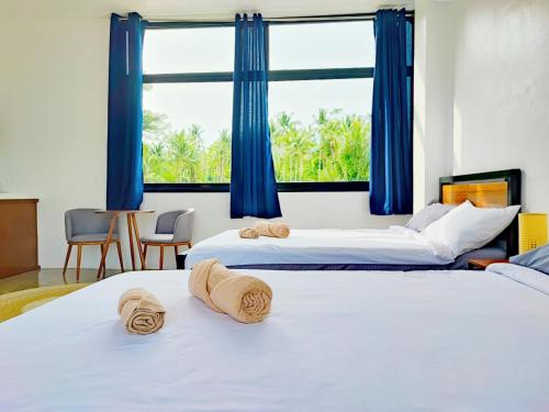 two beds in a room with blue curtains at Casa Basa Siargao in General Luna