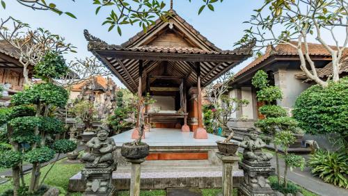 a temple in a garden with statues in front of it at Marwati Guest House in Ubud