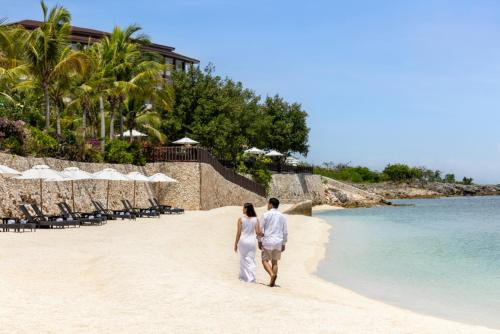 un hombre y una mujer caminando por la playa en Dusit Thani Mactan Cebu Resort, en Mactan