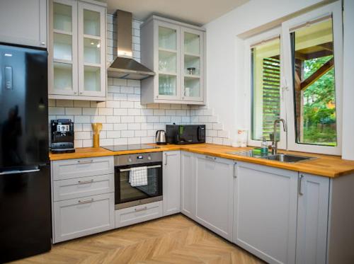 a kitchen with white cabinets and a black refrigerator at Green House Exclusive in Macharce