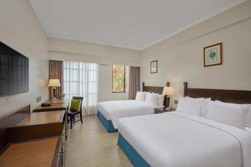 a hotel room with two beds and a desk at Holiday Inn & Suites Batangas LimaPark by IHG in Batangas City