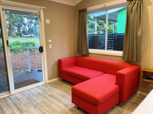 a living room with a red couch and a window at Huskisson Beach Escape in Huskisson