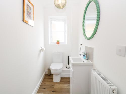 a white bathroom with a toilet and a sink at Pine Cottage in Beccles