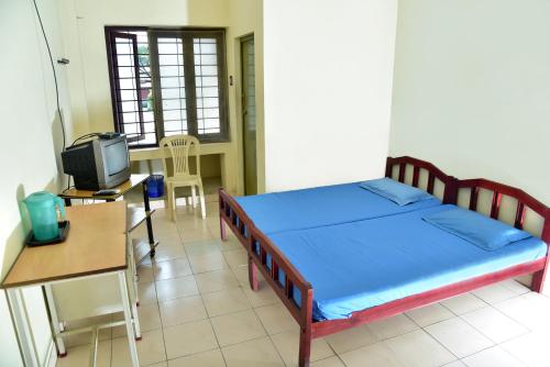 1 dormitorio con 1 cama, escritorio y TV en Sithara Guest House, en Palakkad