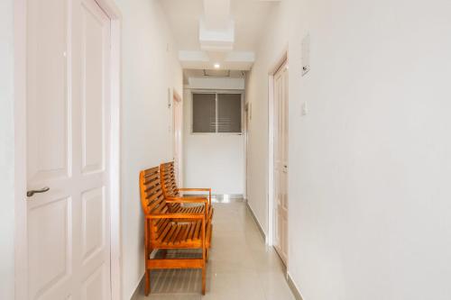 two wooden chairs sitting in a hallway next to a door at OYO KC Arcade in Cochin