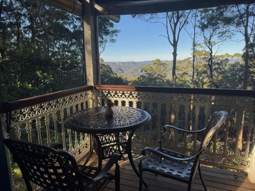 a table and chairs on a balcony with a view at Heaven in the Hills Retreat in Maleny