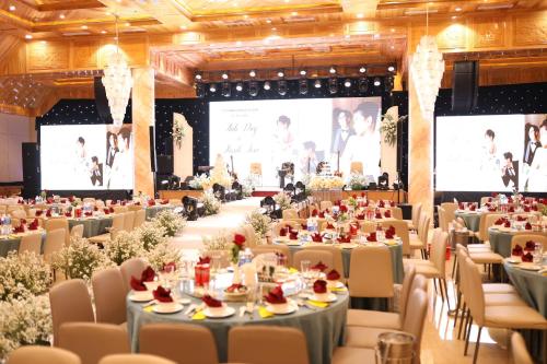 a banquet hall with tables and chairs and projection screens at Phú Long Tam Kỳ Hotel & Restaurant in Tam Ky