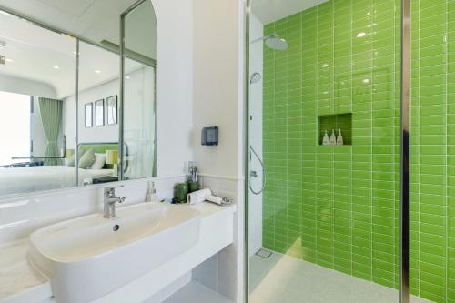 a bathroom with a sink and a shower with green tiles at Rosie Hillside Seaview Phu Quoc Apartment in Phu Quoc
