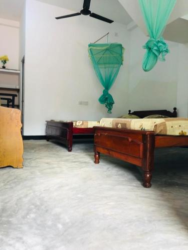 two beds in a room with blue curtains on the wall at Ancient Tree in Mirissa