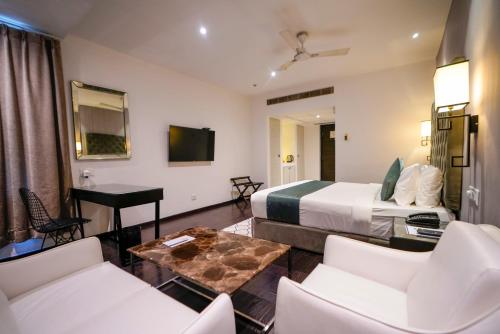 a hotel room with a bed and a table and chairs at Hotel Deccan Serai, HITEC CITY, HYDERABAD in Hyderabad