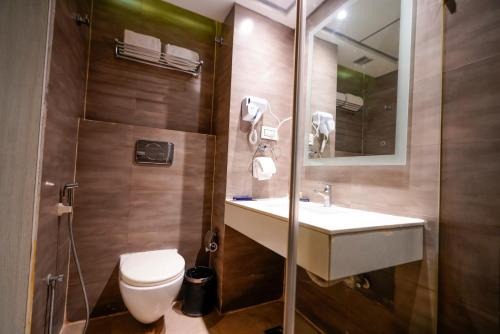 a bathroom with a sink and a toilet and a mirror at Hotel Deccan Serai, HITEC CITY, HYDERABAD in Hyderabad