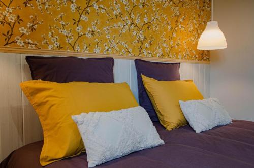a bed with yellow and blue pillows on it at La petite maison dans lusigny in Lusigny-sur-Barse