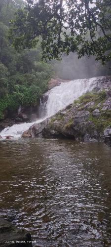 a river with a waterfall on the side of it at Munnar home stay in Munnar