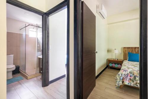 a bedroom with a bed and a bathroom with a shower at Condo Playa Hermosa, Puntarenas in Muñeco