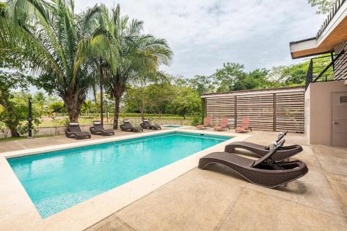 a swimming pool with lounge chairs next to a house at Condo Playa Hermosa, Puntarenas in Muñeco