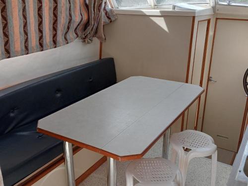 une table et deux tabourets dans une petite pièce dans l'établissement Séjour insolite sur un bateau au cœur de Châtillon-en-Bazois, romantisme et nature inclus - API-1-46-17, à Châtillon-en-Bazois