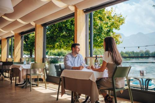 a man and a woman sitting at a table in a restaurant at Parc Hotel Du Lac in Levico Terme