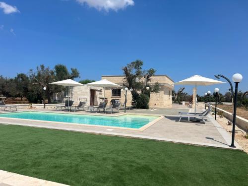 une piscine avec chaises longues et parasols à côté d'une maison dans l'établissement Villa Lara - mit separatem extra Zimmer mit Wc und Dusche, à San Vito dei Normanni