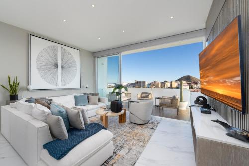 a living room with a white couch and a large window at Apartment with Private Rooftop in Medano in Cabo San Lucas