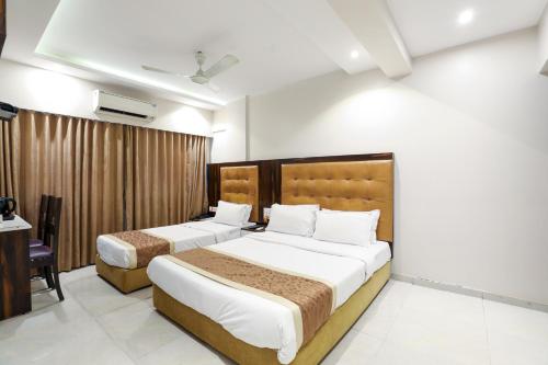 a bedroom with two beds and a desk at Hotel Embassy Park - BKC Mumbai in Mumbai