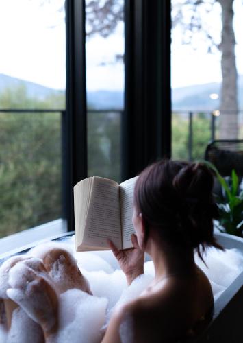 a woman laying in a bath tub reading a book at The View Bright - Apartment 1 in Bright