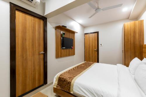 a bedroom with a bed and a tv on the wall at Hotel Embassy Park - BKC Mumbai in Mumbai