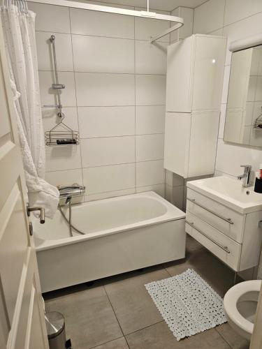 a white bathroom with a tub and a sink at Rooms with free parking in Lillestrøm
