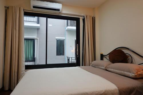 a bedroom with a bed and a large window at Cozy house in Chiang Mai