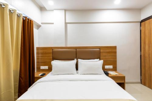 a bedroom with a large bed with a wooden headboard at Hotel Embassy Park - BKC Mumbai in Mumbai