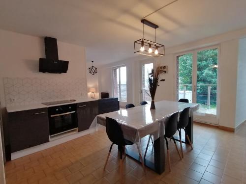une cuisine et une salle à manger avec une table et des chaises blanches dans l'établissement Ô pilotis Appartement avec terrasse et jardin, au Tréport