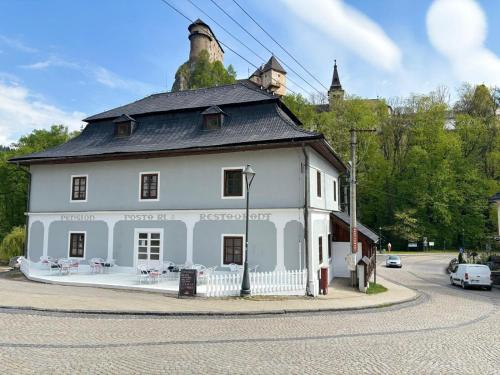 a white house with a black roof on a street at Boutique Hotel Pošta RL in Oravský Podzámok