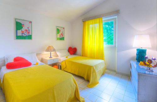 a bedroom with two beds with yellow sheets and a window at Villaggio Riva Musone in Porto Recanati
