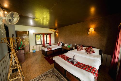 a bedroom with two beds and a fan at Wild Adventure Resort in Sauraha