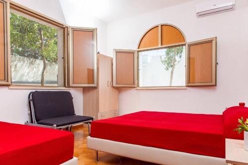 a bedroom with two beds and a chair and windows at Villa Kareema 1A con accesso diretto alla Spiaggia di San Pietro in Bevagna in San Pietro in Bevagna