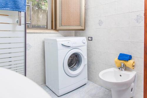 a bathroom with a washing machine and a sink at Villa Kareema 1A con accesso diretto alla Spiaggia di San Pietro in Bevagna in San Pietro in Bevagna