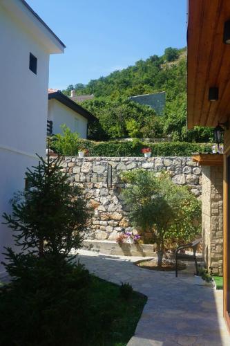 a stone wall and a bench in a yard at Hill Homes Montenegro in Petrovac na Moru