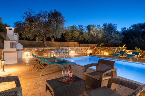 una piscina con sillas y una mesa junto a ella en Villa Roi, en Kalathos