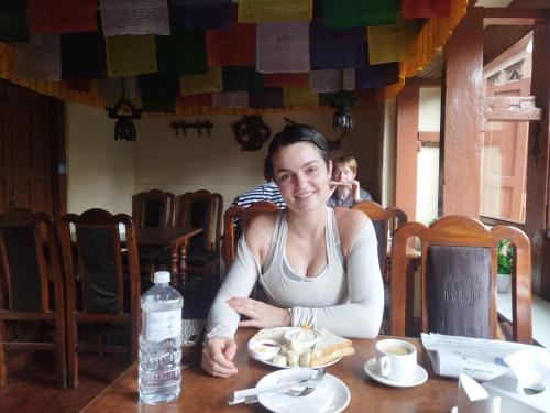 a woman sitting at a table with a plate of food at HOTEL RUPAKOT AND ROOFTOP RESTAURANT in Bhaktapur