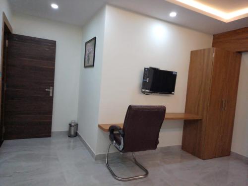 Habitación con silla y TV en la pared. en Groves, en Ranchi