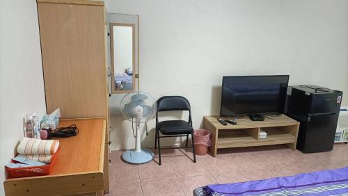 a living room with a television and a desk with a chair at 頭城旅宿 in Toucheng