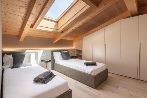 two beds in a room with wooden ceilings at Lago Dorato Luxury Apartments - Lake Como View in Colico